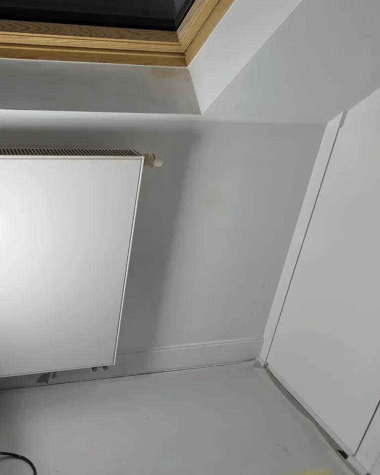 Professioneel binnenschilderwerk in een badkamer op zolder met strak afgewerkt plafond en zorgvuldig beschermde werkruimte