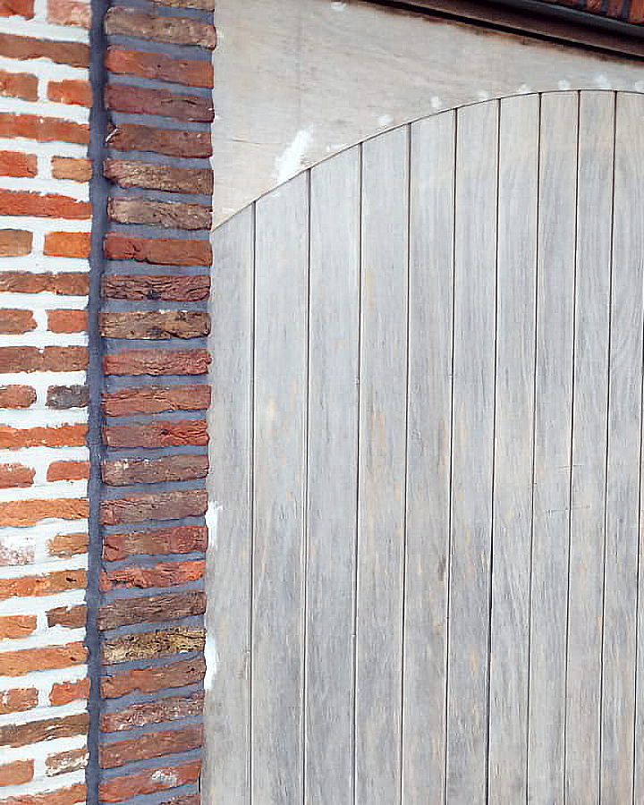 Geschuurde houten garagepoort als voorbereiding op professioneel buitenschilderwerk.