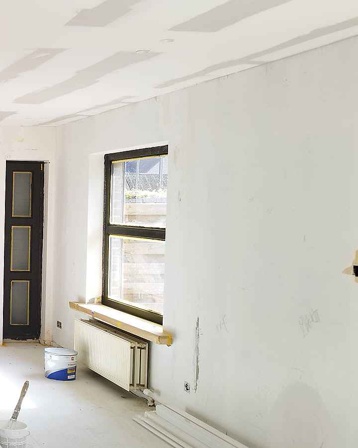 Voorbereiding en schilderwerken van muren en plafond tijdens een interieurrenovatie.