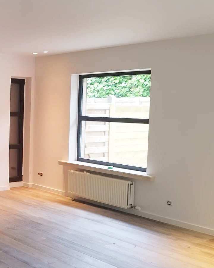 Strak geschilderde binnenmuren in een moderne leefruimte met houten vloer.
