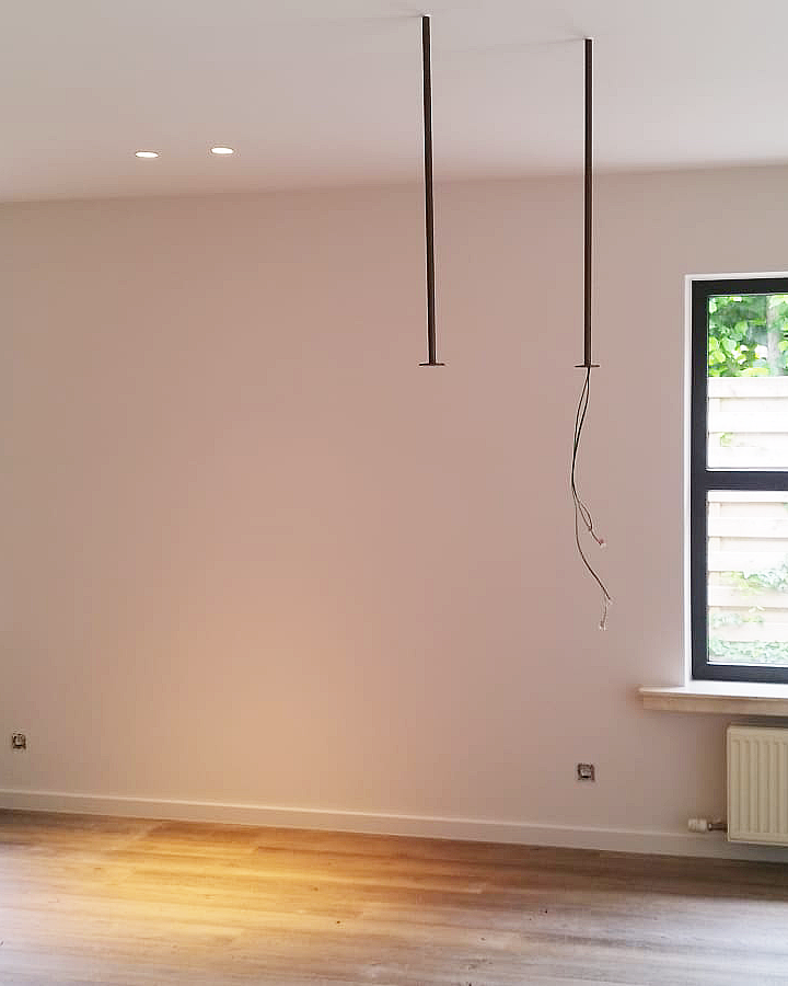 Glad en strak afgewerkte witte binnenwand in een moderne leefruimte.