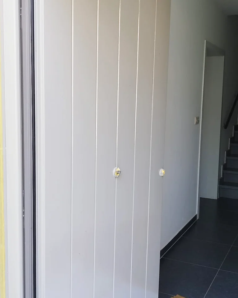 Detail van het strakke lakwerk op een binnendeur met verticale panelen.