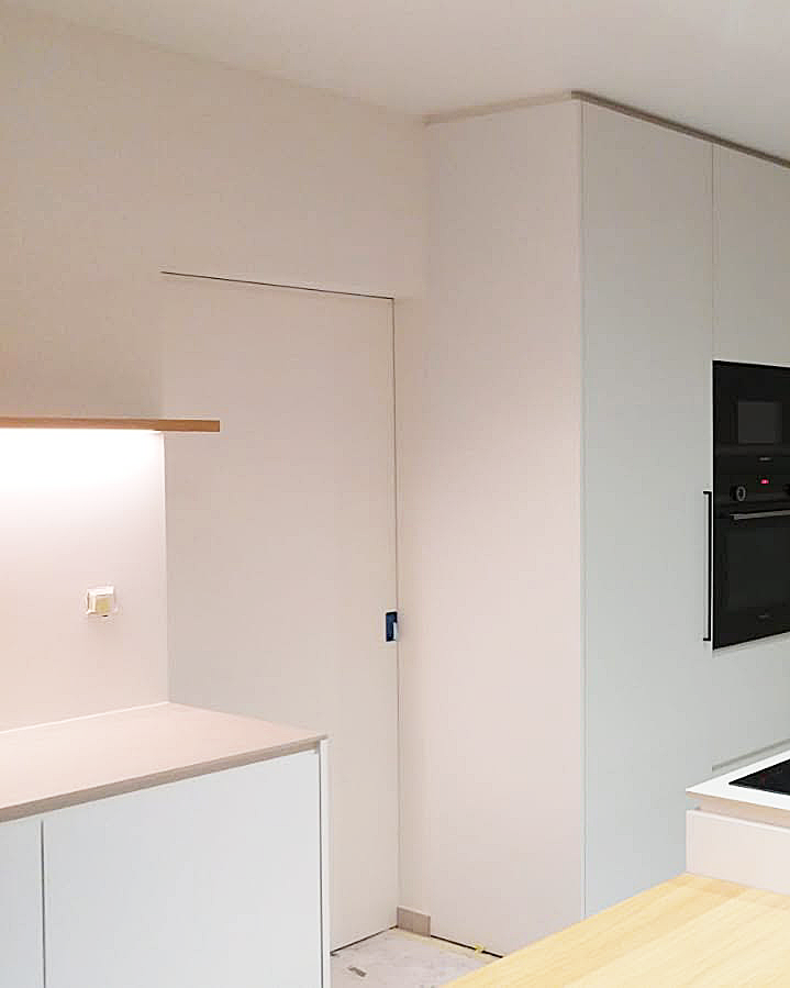 Strak geschilderde keuken met glad afgewerkte muren.