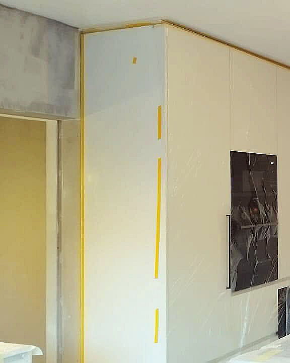 Plamuurwerken in keuken met zorgvuldig beschermde meubels.